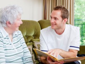 Young male carer reading to elderly woman