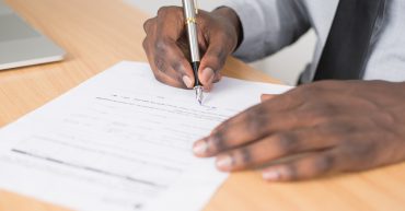 Man holding a pen completing an application form