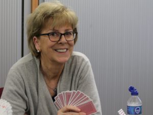 Woman in grey cardigan holding playing cards