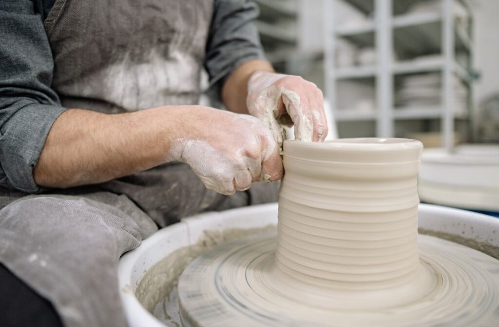 a potter spinning a pottery vessel on a wheel