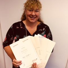 Lady with blond curly hair holding certificates