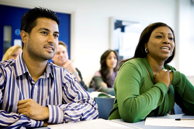 A man and a woman sitting at a desk in a classroom