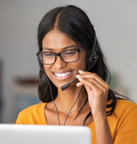 Smiling young woman at home with headset doing video call