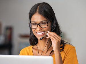 Smiling young woman at home with headset doing video call
