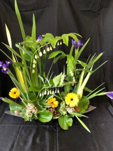 Floral design with green foliage and yellow gerbera flowers