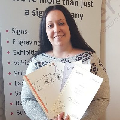 lady with long dark hair holding certificates