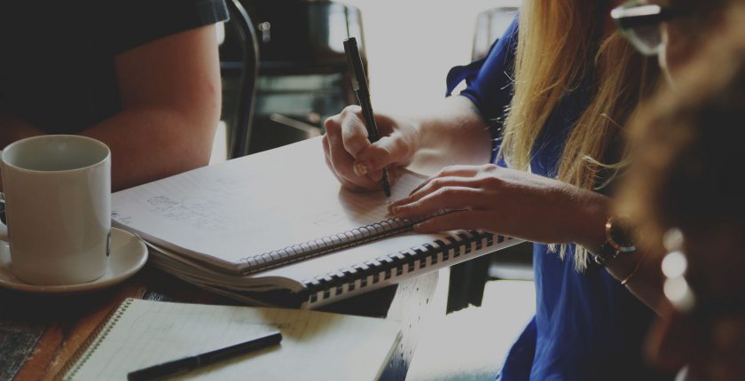 Woman writing on notepad in cafe