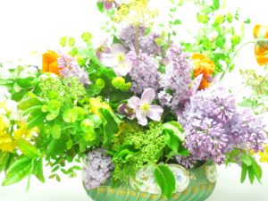 Flower arrangement in vase with lilacs and green foliage