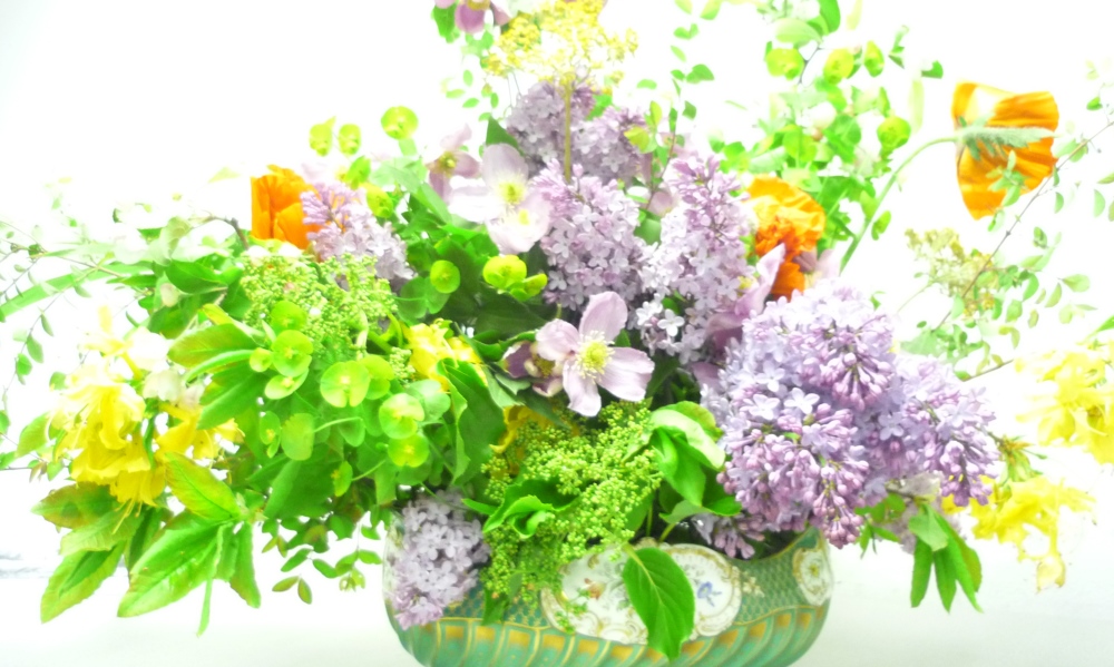 Flower arrangement in vase with lilacs and green foliage
