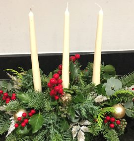 Christmas floral arrangement with candles and berries