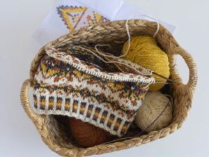 A basket with a fair isle knitting project and balls of wool