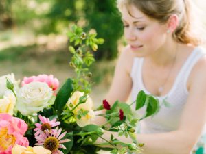 Woman in white vest arranging pink and white flowers