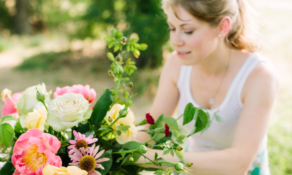 Woman in white vest arranging pink and white flowers