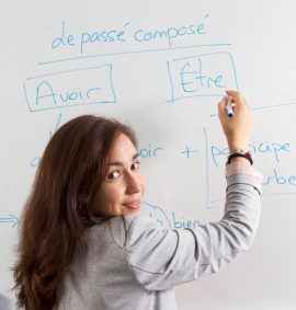 Woman writing on French verbs on whiteboard