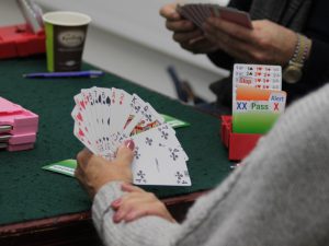 Woman in grey sweater holding cards for bridge game