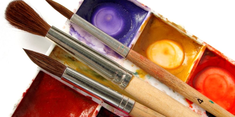 Three paintbrushes and paint palette