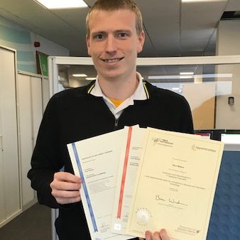 Young man with blond hair holding certificates