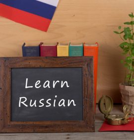 Blackboard with Learn Russian written with pencils and books behind