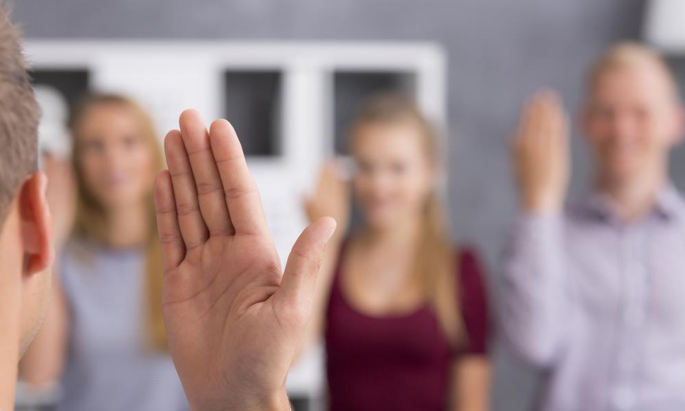 Hand using sign language with three people in background
