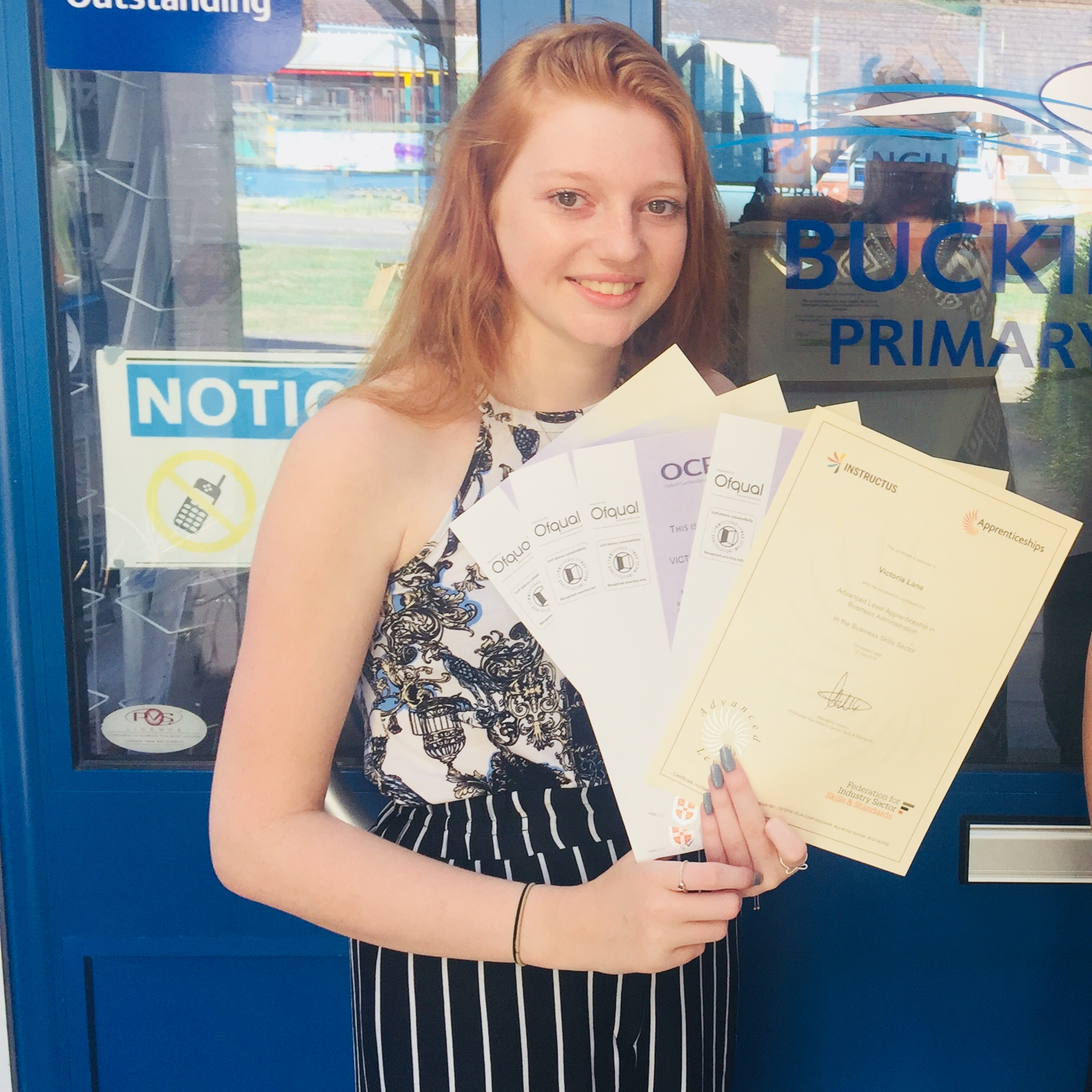 Girl with red hair holding certificates outside a door