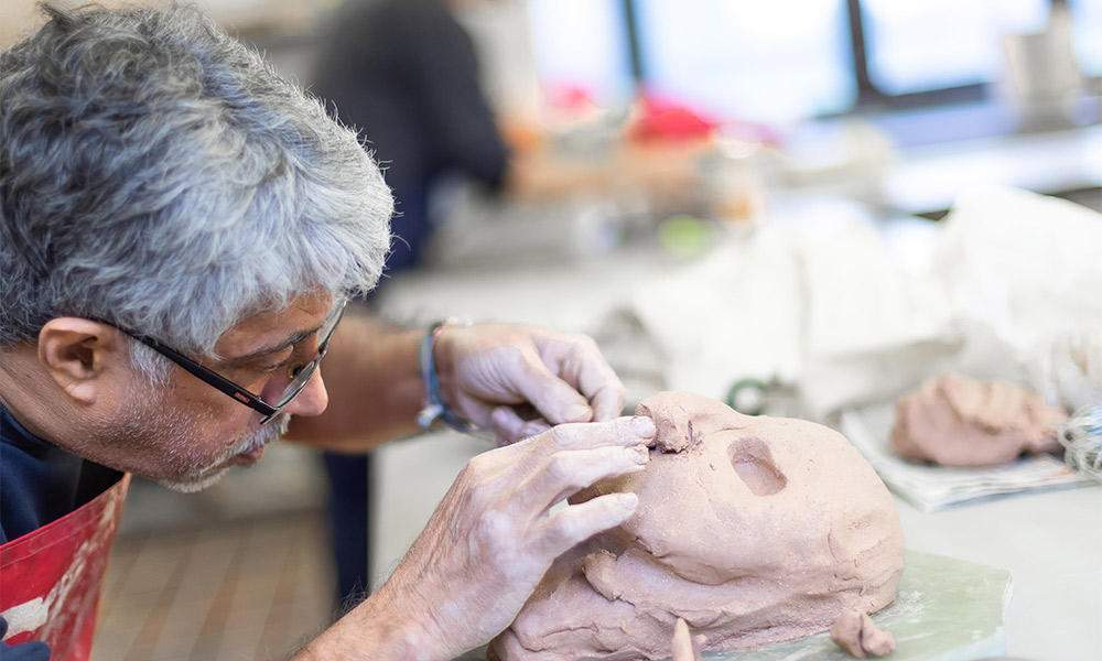 man sculpting a face in clay