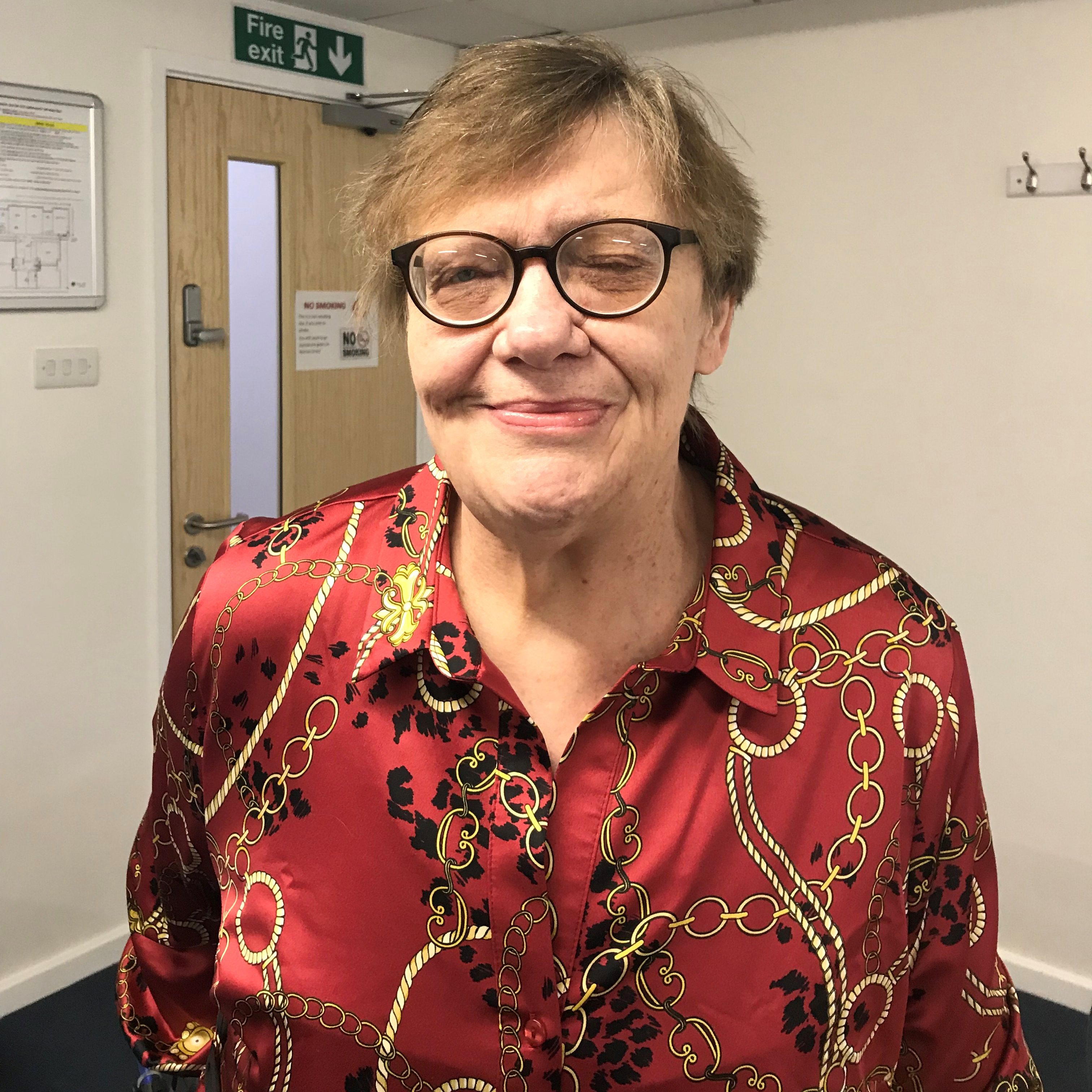 Lady in glasses wearing red shirt in front of door