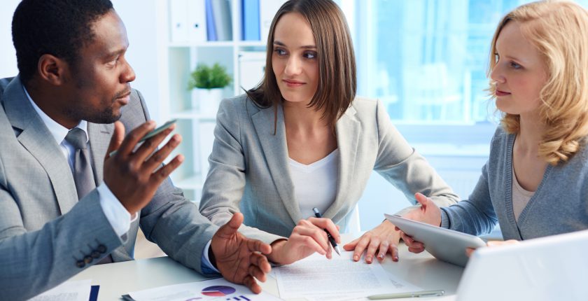 Man and two women in a meeting at a desk with a laptop