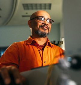man wearing eyeglasses facing computer