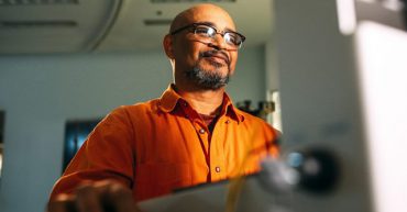 man wearing eyeglasses facing computer