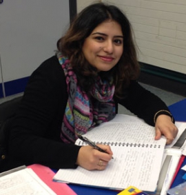 Women student smiling and writing notes in her notepad on a desk at Buckinghamshire Adult Learning